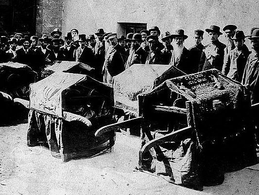 Black and white photograph of people at a funeral. 