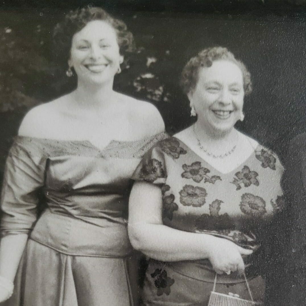 Two ladies standing next to each other and smiling. 